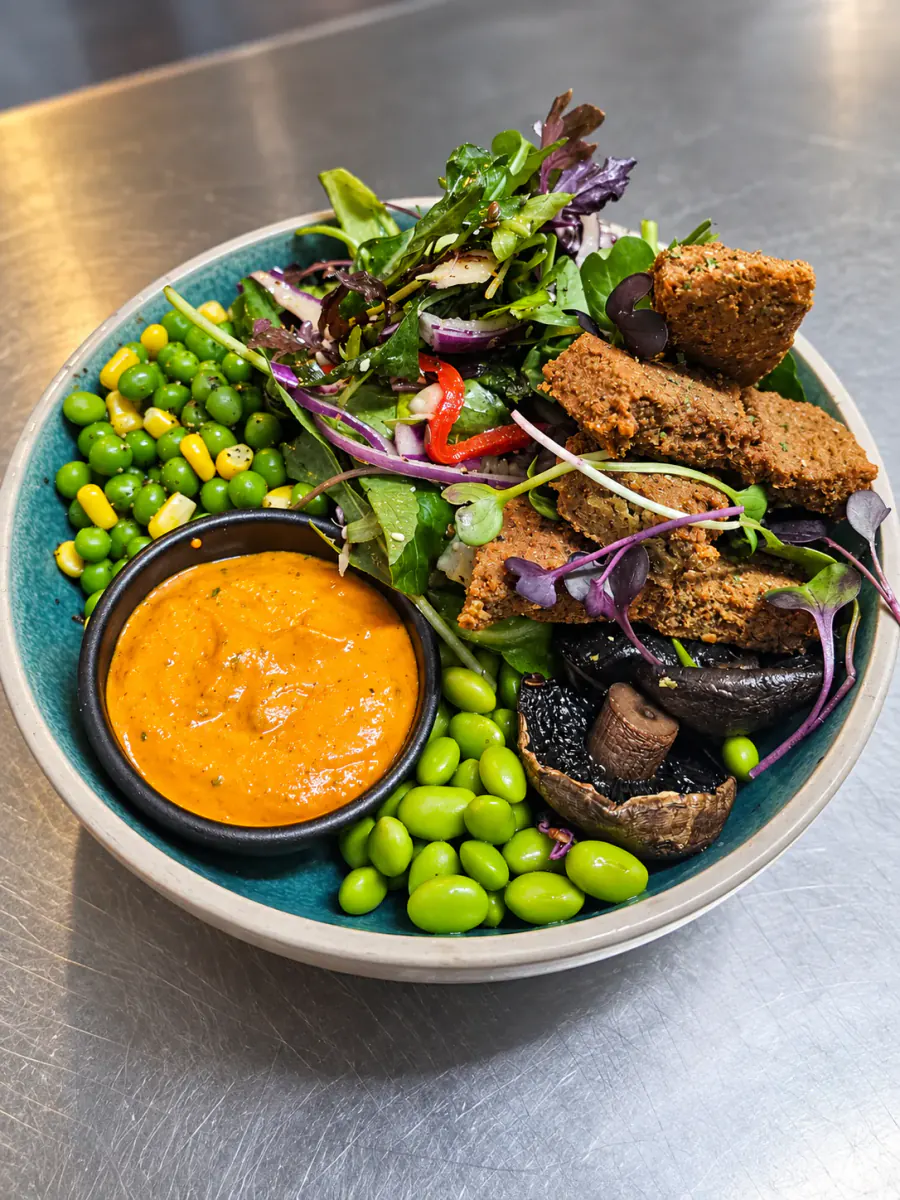 A green salad bowl with crisp bites and dipping sauce